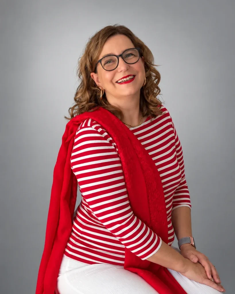 Michaela Werner sitzend im rot-weiß gestreiften Shirt mit rotem Schal, lächelnd in die Kamera