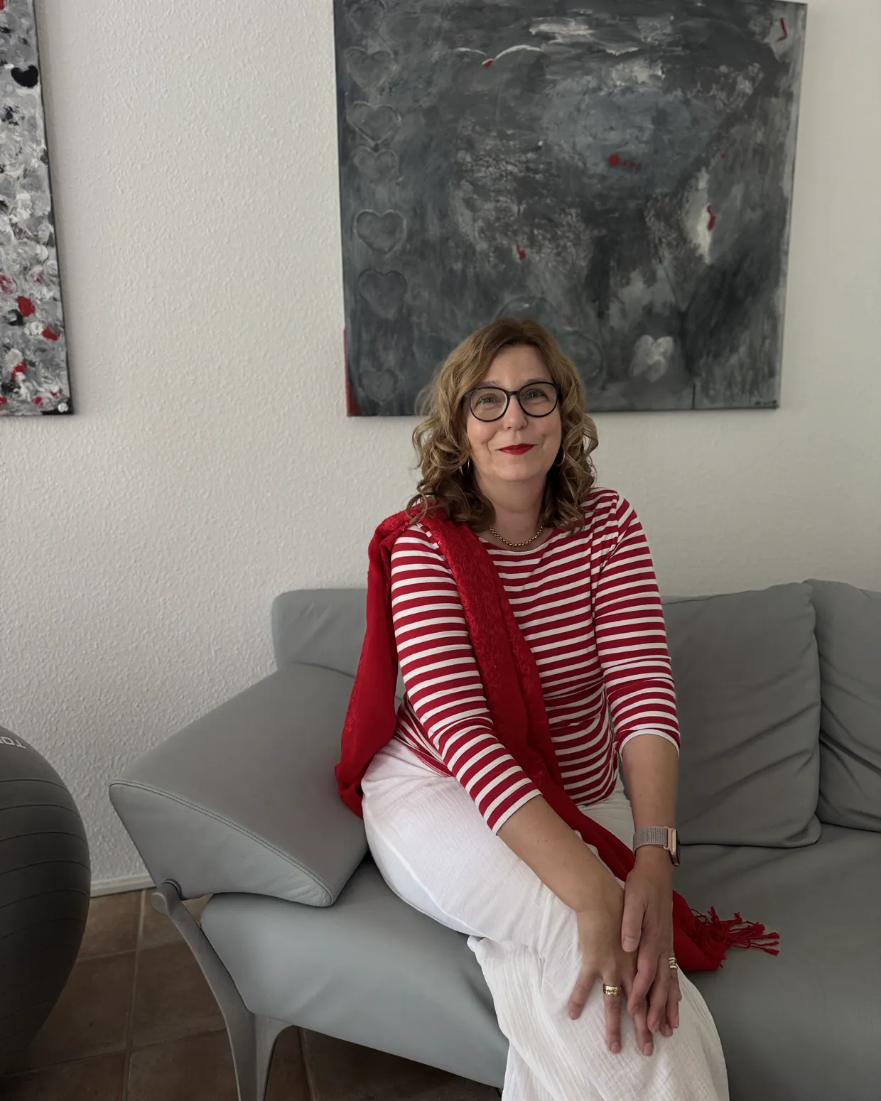 Porträt von Michaela Werner, sitzend auf einem Sofa vor einem großformatigen Bild